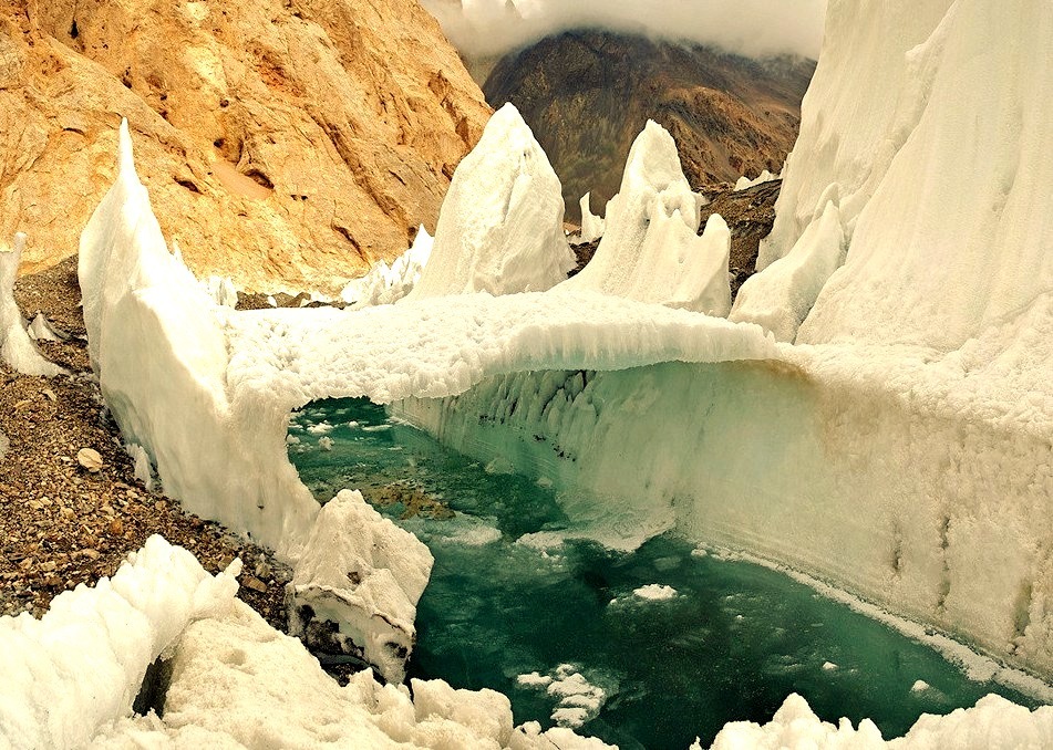 Melting river and frozen bridge in one of Central Asia glaciers
